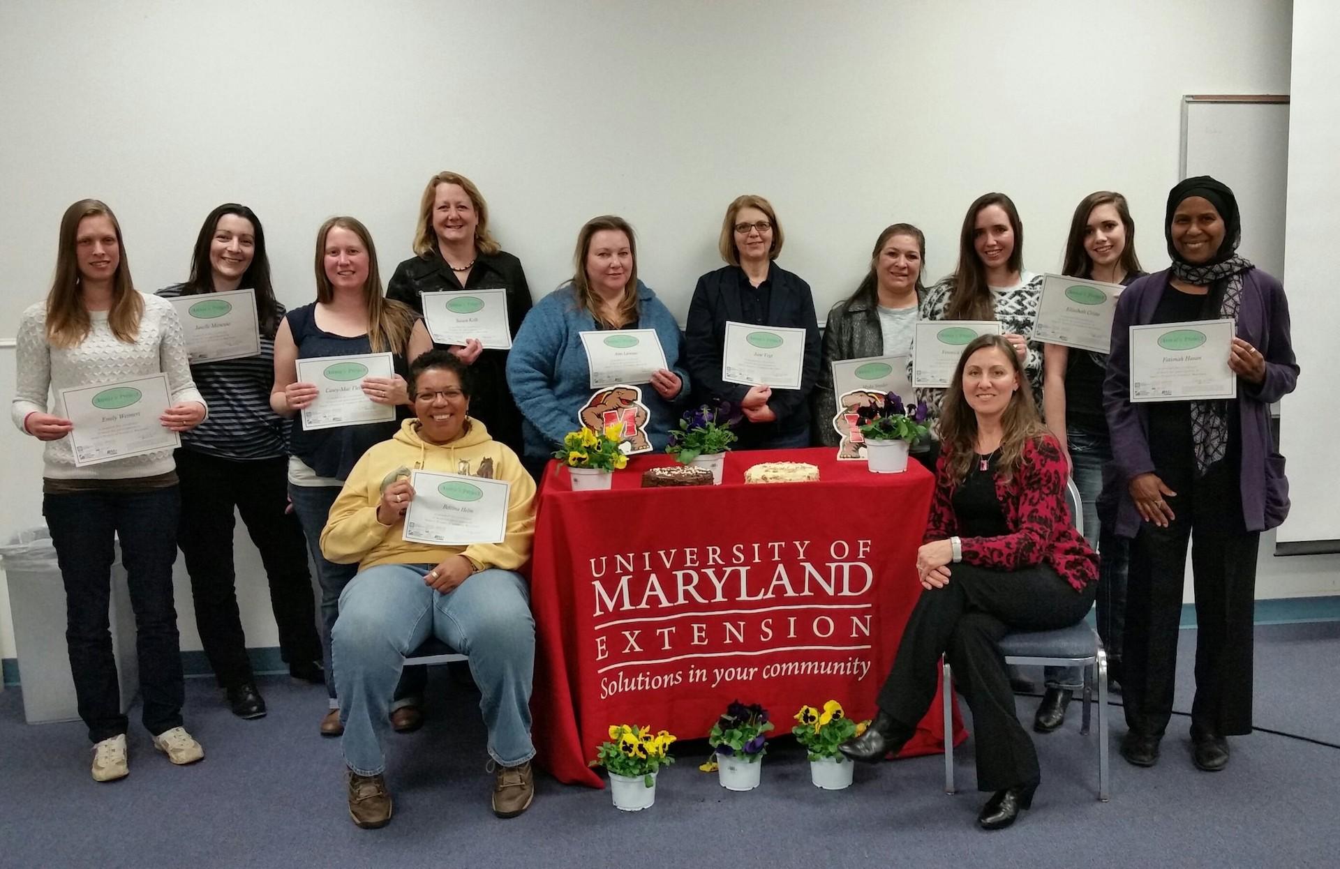Annie's Project Class holding their certificates in front of a University of Maryland Extension table