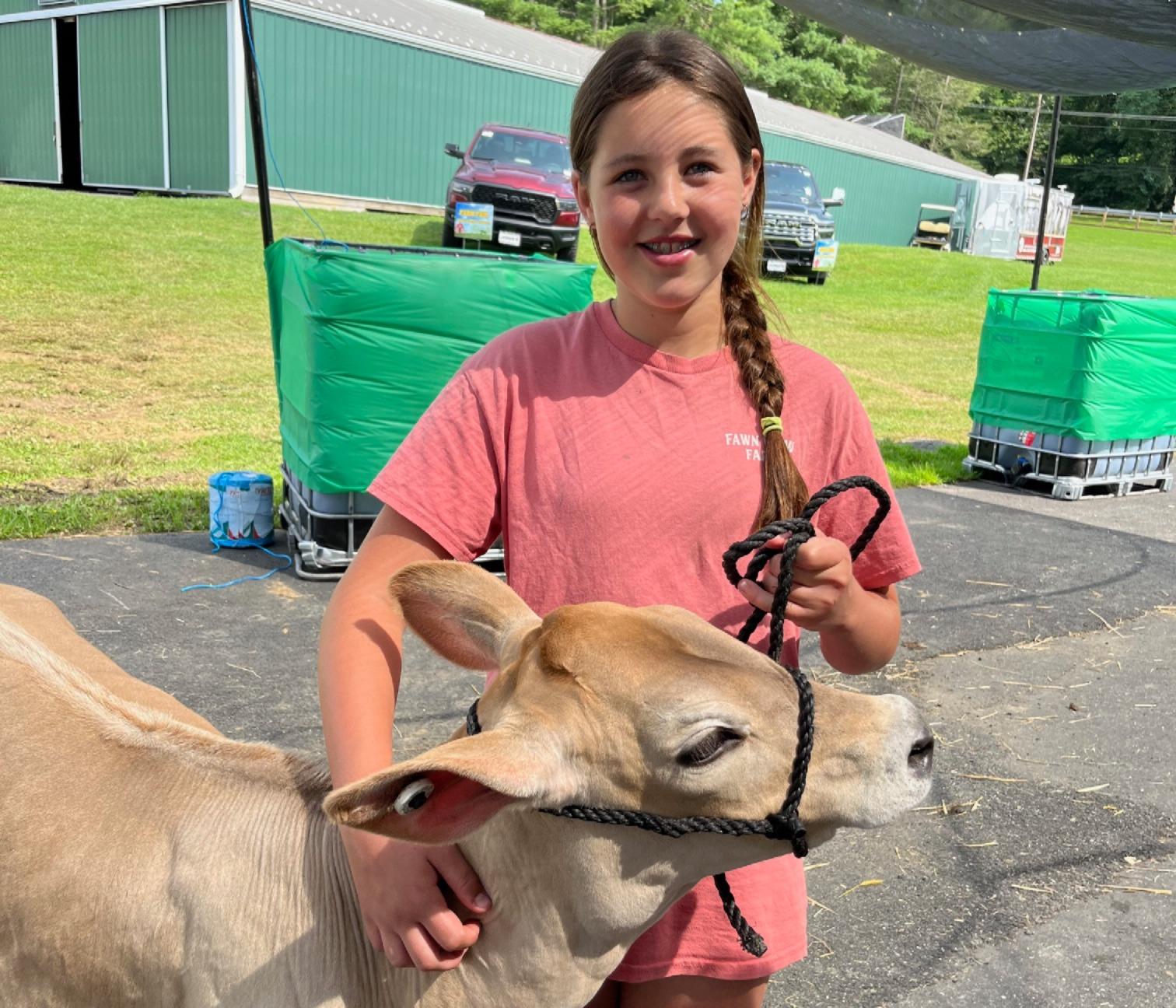 4-H child standing outside with her dairy calf