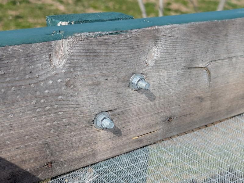 A close-up of bolts anchoring a leg to a Salad Table frame, as seen from inside of the table top.