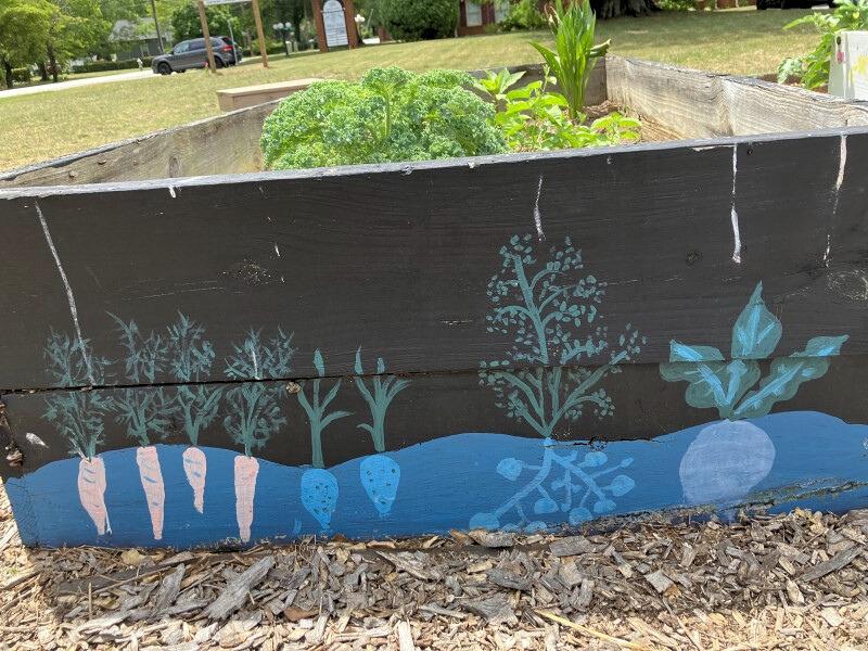 Side view of a raised bed painted with a motif of carrots and other root vegetables.