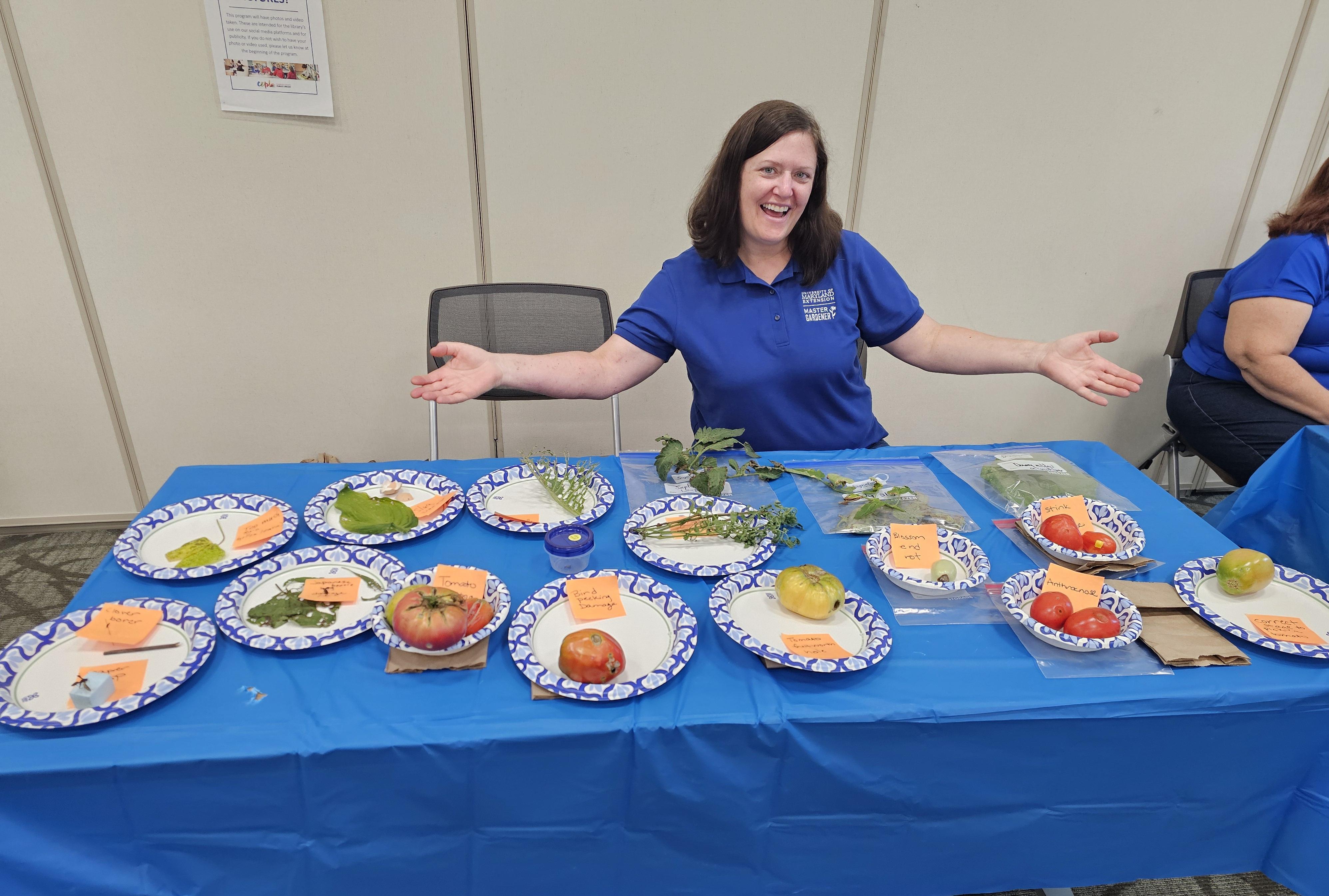Woman displaying a table of diseased or pest-infested fruits and vegetables