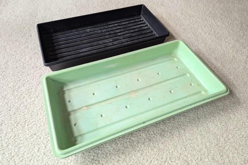 Two designs of similar-sized sturdy plastic trays with no drainage holes.