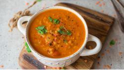 Red Lentil Soup inside a white bowl on top of a cutting board on a table
