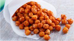 Roasted Chickpeas falling out of a cone of rolled parchment paper on a table