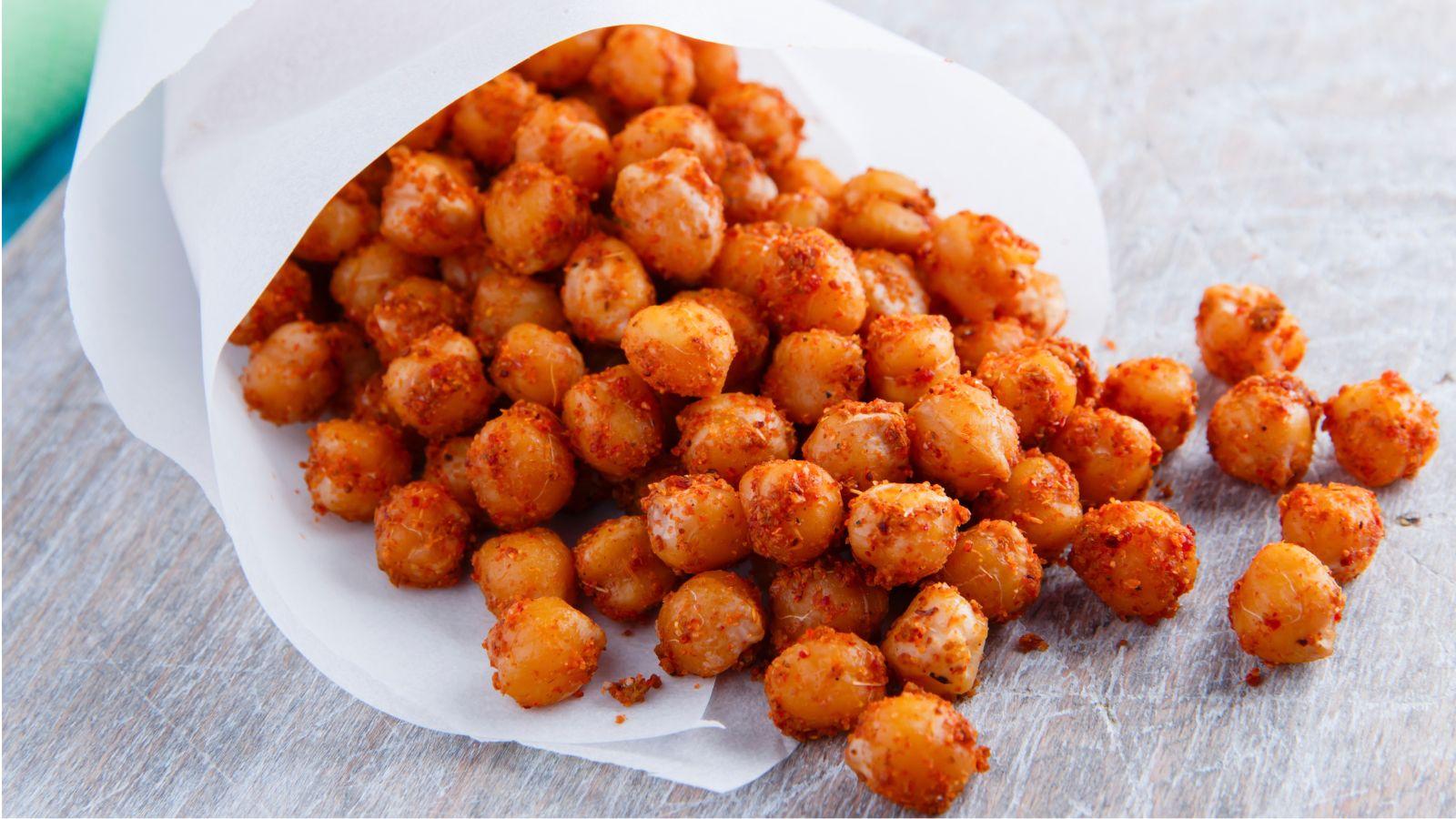 Roasted Chickpeas falling out of a cone of rolled parchment paper on a table