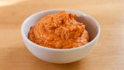 White bowl of romesco sauce sitting on wood table