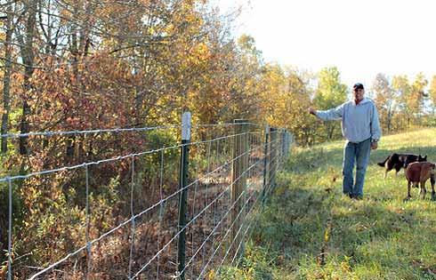 Man standing by a wire fence, Photo: USDA blog at http://blogs.usda.gov/2013/01/24/retiree-improves-and-diversifieskentucky- farm-for-future-generat ions/