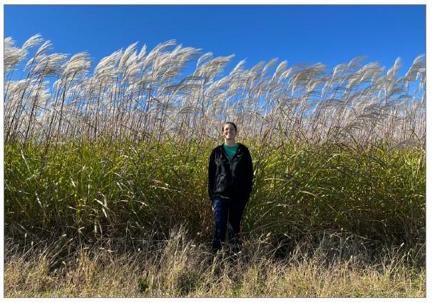Sarah Hirsh is standing in front of a field of giant miscanthus.