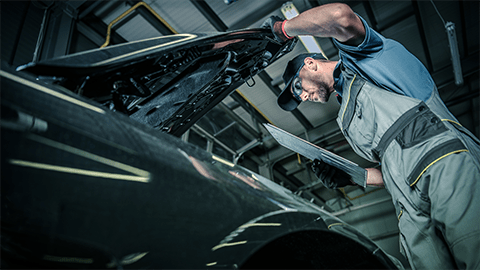 A mechanic examines and checks the warranty on a defective car battery to see if the owner qualifies for a free replacement.