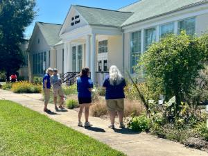 4 people outside a building visiting a garden with plants and flowers