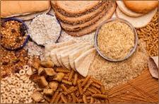 Assorted carbohydrates including bread slices, pasta, rice, oats, and cereals are spread out, showcasing a variety of grains.