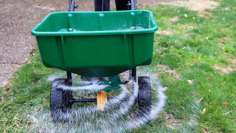 Wheeled walk-behind lawn spreader consisting of a basin that empties onto a rotating disc that flings the material onto the lawn.
