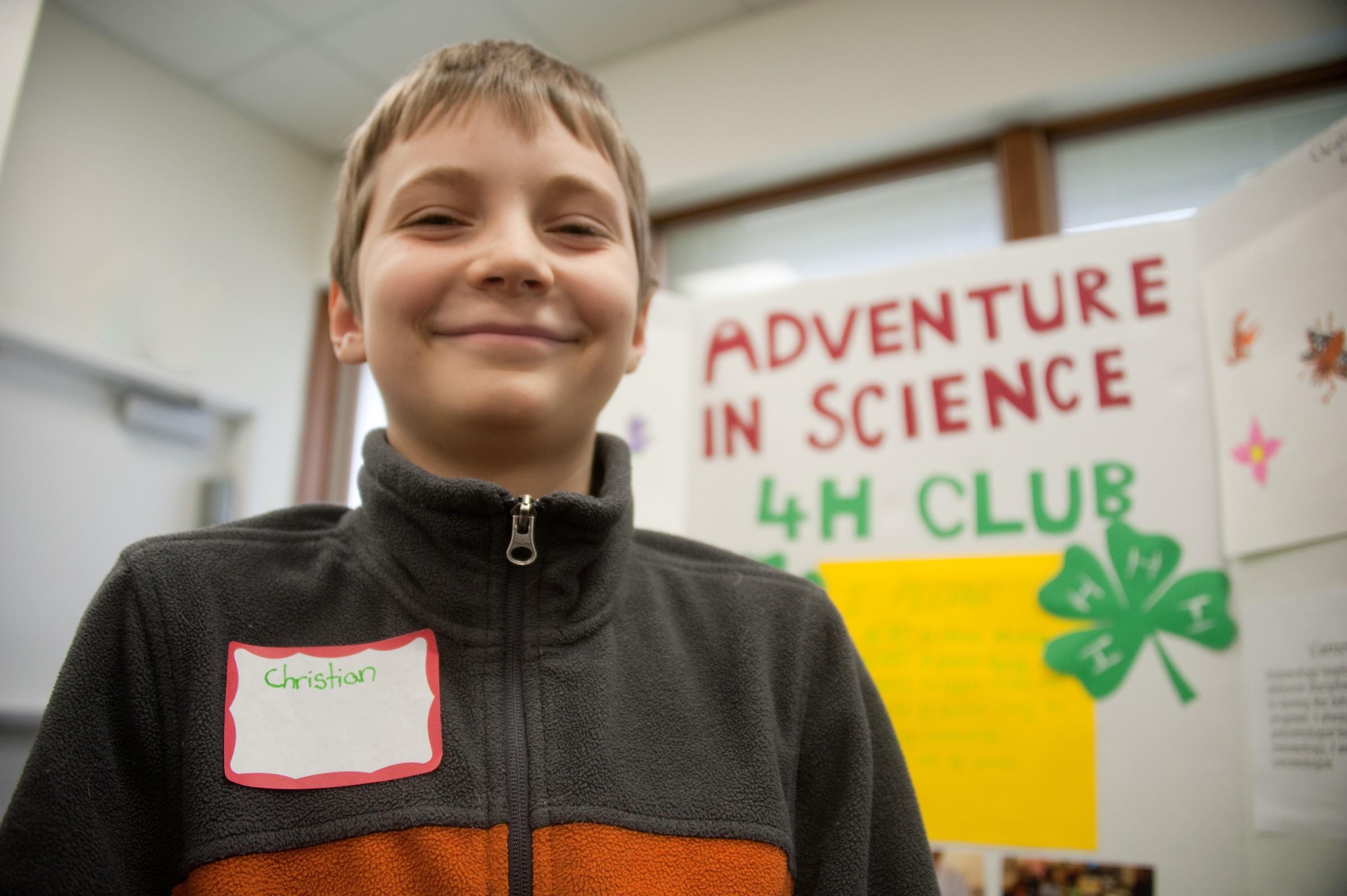 Kid smiling in-front of a 4H club poster
