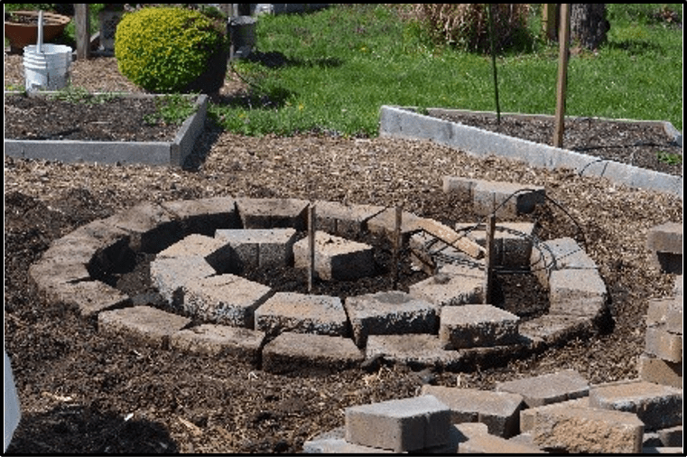 First layer of an herb spiral using concrete pavers in a circular direction