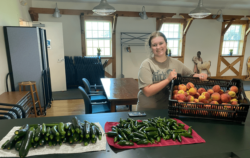 Teagan with harvested peaches, jalapeños and zucchini