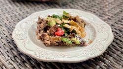 chilaquiles con frijoles on a white plate on a wicker table