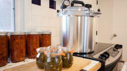 home kitchen featuring a counter next to a stove with a pressure cooker and jarred vegetables on the counter