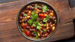 vegetarian chili topped with cilantro in a dark bowl on a wooden cutting board