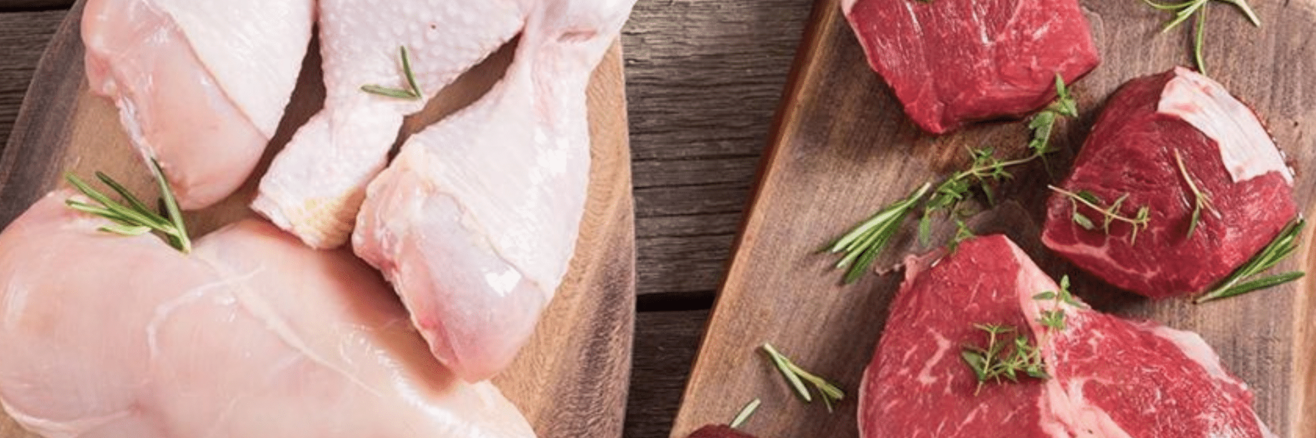Raw poultry and beef sitting on wood plank serving boards.